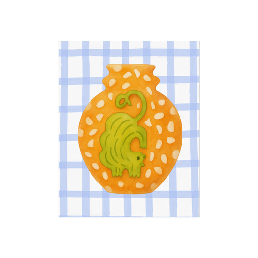 Decorative tile with a ochre cat design on an orange background, set against a blue checkered pattern.