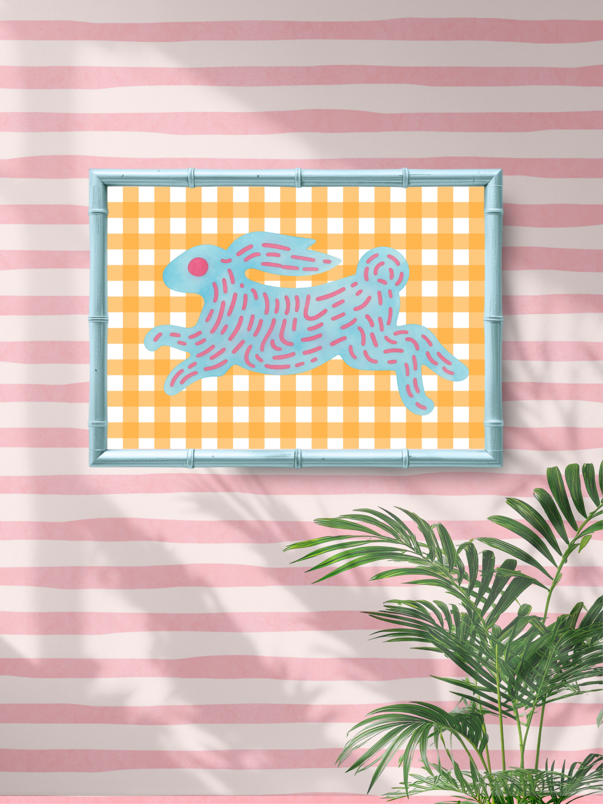 Framed artwork of a blue rabbit on a yellow checkered background, with pink and white striped wall and plant in the foreground.