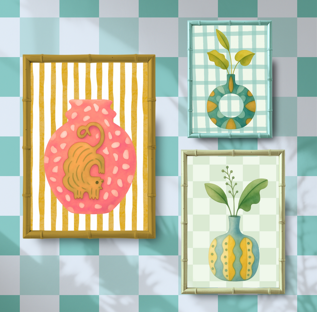 Colorful gallery wall featuring three framed whimsical art prints with checkered backgrounds, including a pink cat illustration and two decorative vases in soft pastel tones.