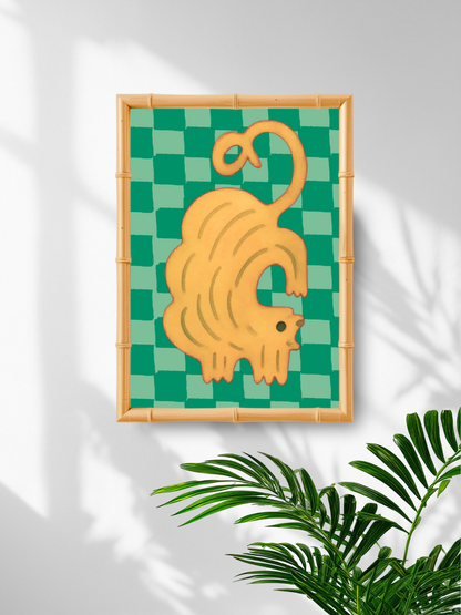 Framed artwork of a yellow cat on a green checkered background with plant leaves in the corner.