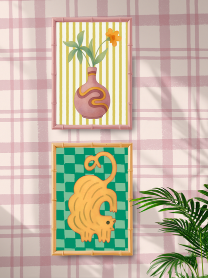 Two framed artworks on a wall with a pink plaid pattern