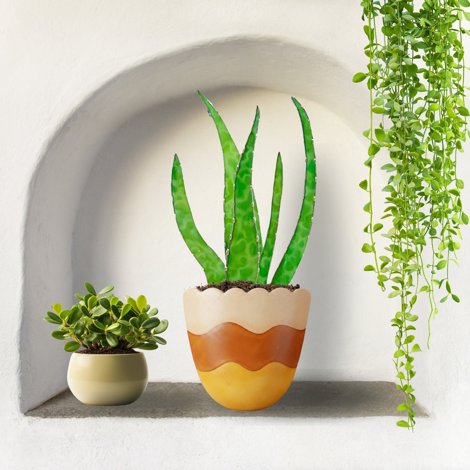 Stained glass aloe plant decor with green glass leaves in a decorative pot, styled in a wall niche with houseplants, modern botanical home decor.